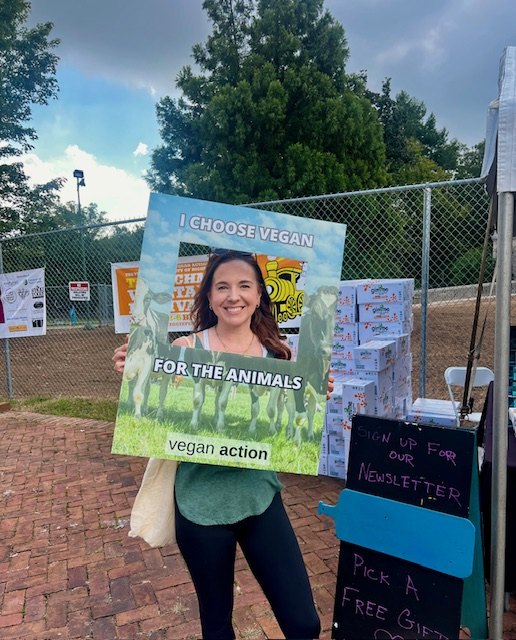 Jennifer at a vegan community event holding an I Choose Vegan for the Animals sign